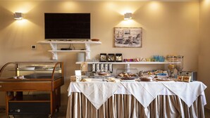 A buffet setup with a variety of food items, a television, and decorative wall art.
