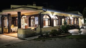 A hotel with a patio area, outdoor seating, and a well-lit entrance.