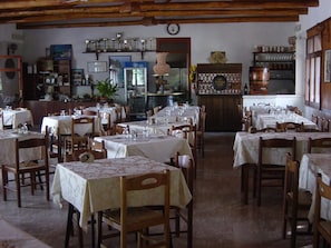 Um restaurante com várias mesas e cadeiras, um espaço de bar e uma vitrine com troféus na parede.