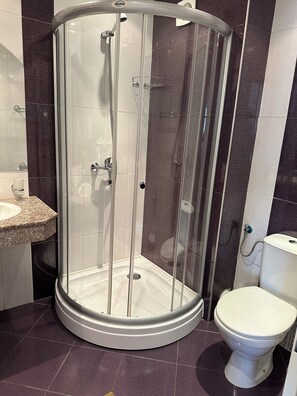 A bathroom with a glass-enclosed shower, a sink, and a toilet. - Sunny Day Club (Nessebar)