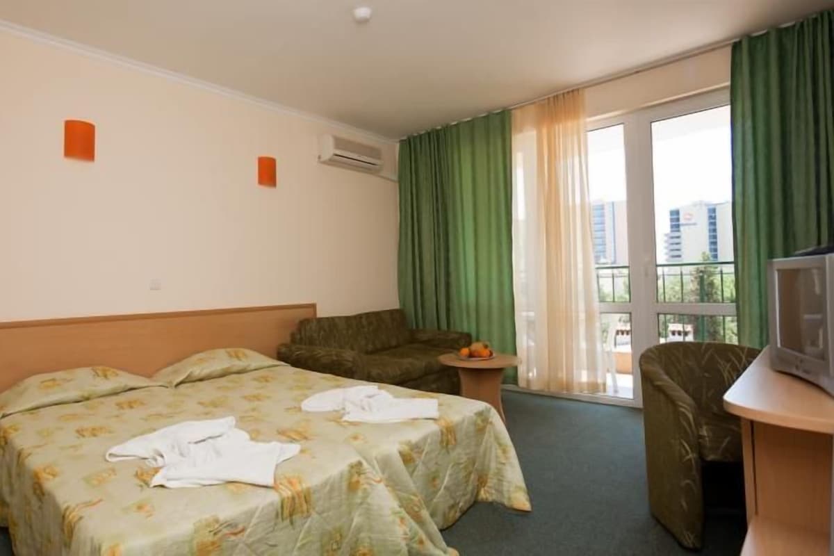 Habitación de hotel con dos camas, un sofá, un televisor y un balcón con cortinas.