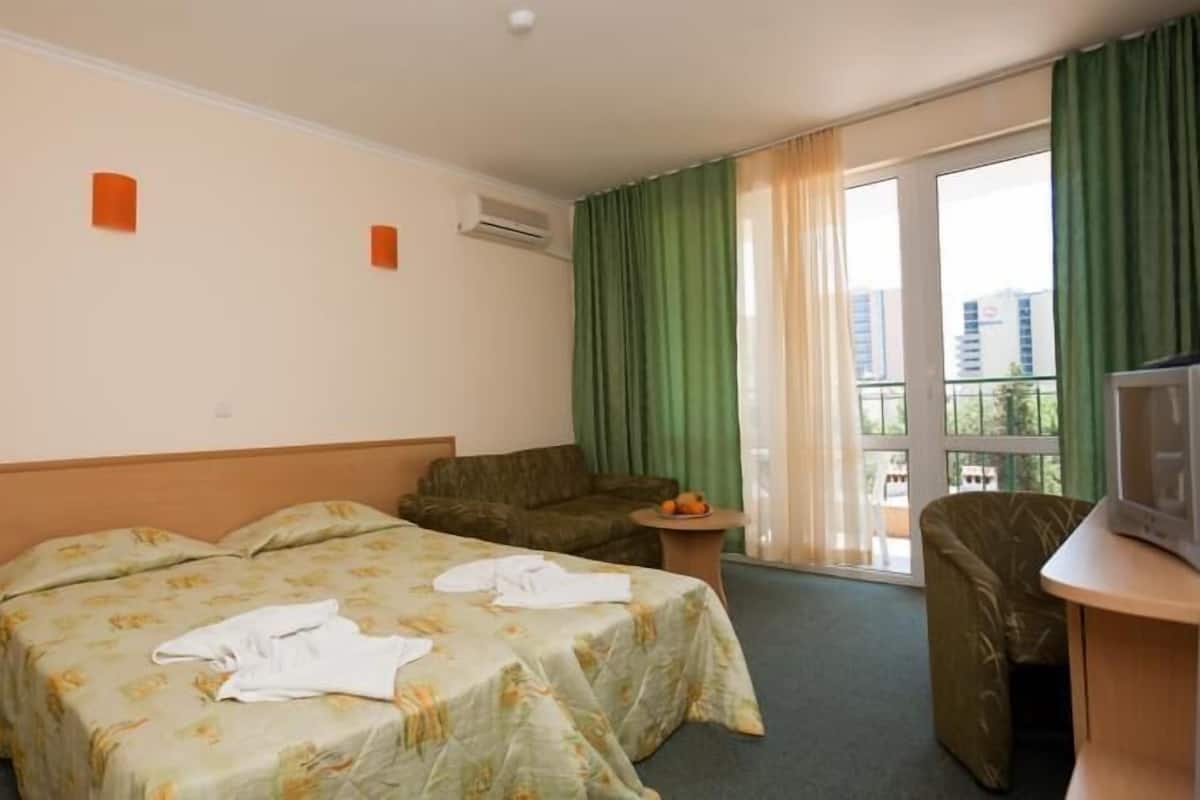 A hotel room with two beds, a sofa, a TV, and a balcony with curtains.