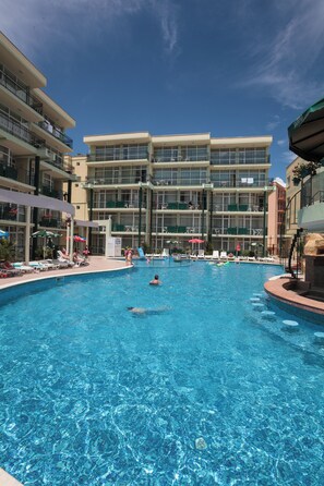 A hotel pool area with multiple levels of balconies, lounge chairs, and umbrellas. - Sunny Day Club (Nessebar)