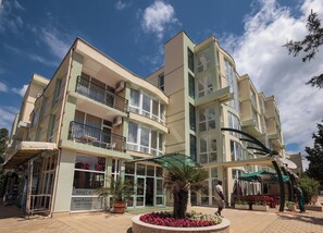 Un hotel de varios pisos con balcones, un letrero de 'Warsteiner' y un cartel que indica 'Mejor Precio 20€'.