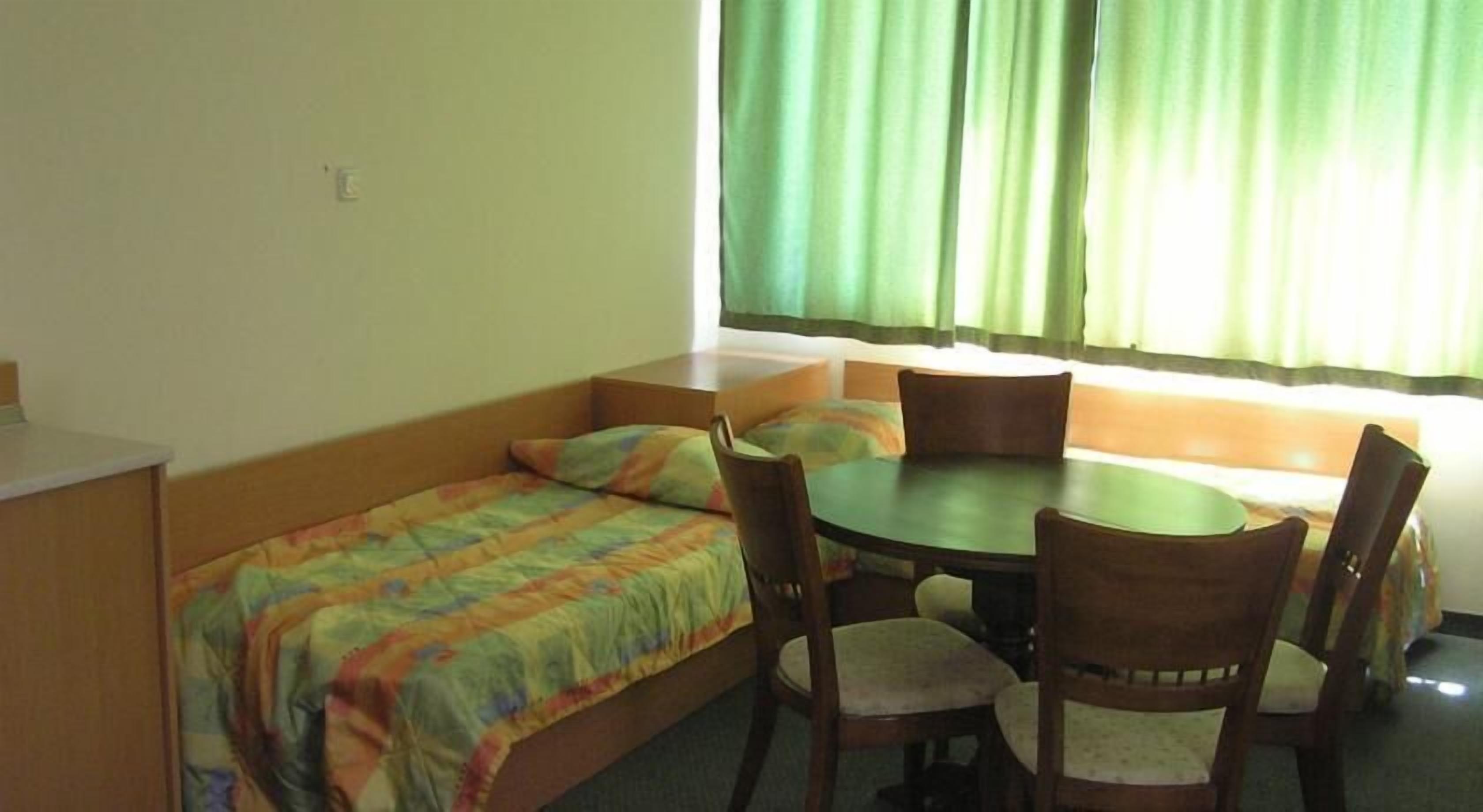 A small room with a bed, a table, and four chairs.