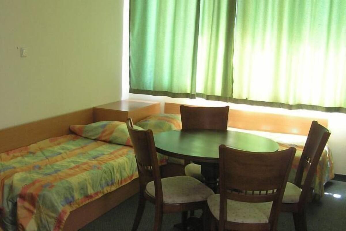 A small room with a bed, a table, and four chairs.