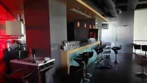 A modern bar area with stools, a counter with glasses, and a red accent wall. - Hotel Satkar Residency (Thane)