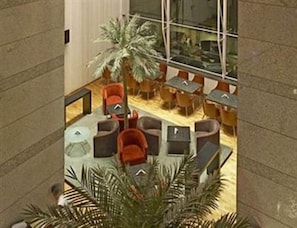 Relax in a casual dining or socializing space with comfortable seating and a lush palm tree.
