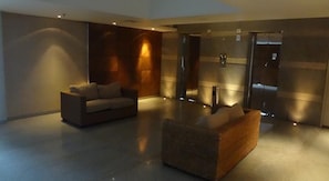 Relax in our comfortable seating area, featuring two sofas and an armchair, near the reception desk with a clear view of the staff area.