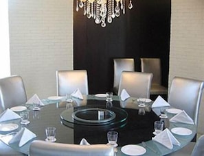 A beautifully set dining area with a round table and six chairs, complete with white plates and clear glasses.