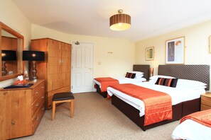 A bedroom with two beds, a wooden wardrobe, a desk with a lamp, and a door. - O'donnabhain's Guesthouse (Kenmare)