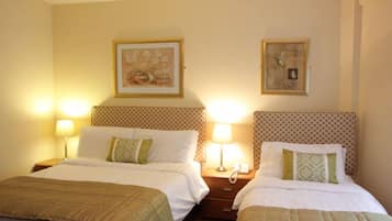 A hotel room with two beds, each with a headboard, bedside lamps, and a telephone on the nightstand.