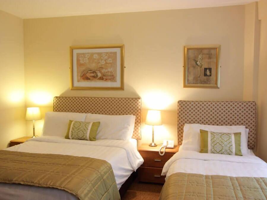 Quarto de hotel com duas camas, cada uma com cabeceira, abajures e telefone na mesa de cabeceira.