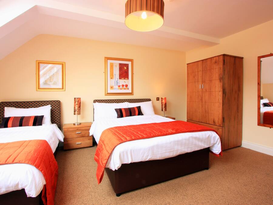 A hotel room with two beds, a wardrobe, and a mirror.