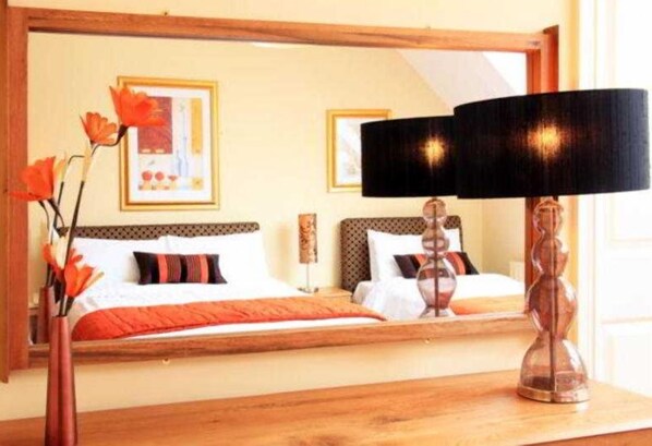 A hotel room with a bed, a mirror, a lamp, and a vase with flowers. - O'donnabhain's Guesthouse (Kenmare)