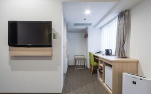 A small room with a TV mounted on the wall, a desk with a chair, and a radiator. - Cityroute Hotel (Osaka)