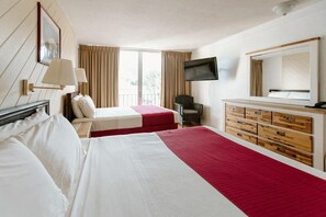 A hotel room with two beds, a TV, a chair, and a dresser. - Hotel On The Cay (Christiansted)