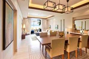 A modern hotel room with a dining area, a large window with a view, and a well-lit space.