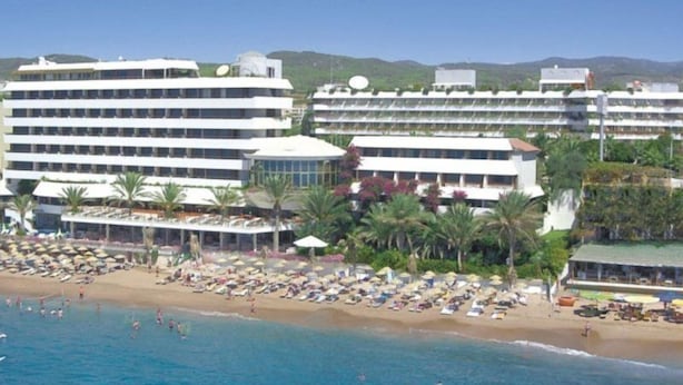 A hotel with multiple floors, a beach with umbrellas, and a clear view of the sea. - Rubi Hotel (Alanya)