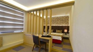 A compact hotel room with a bed, bedside table, lamp, and a desk with a chair. - Istcity Hotel (Istanbul)