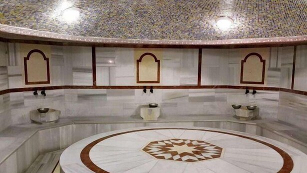 A circular marble fountain with geometric patterns, surrounded by marble walls with decorative arches and small vases. - Istcity Hotel (Istanbul)