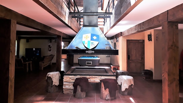 Ein rustikales Interieur mit einem großen Kaminofen, Holzbalken und einem Fliesenboden.