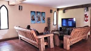 Ein Wohnzimmer mit Holzmöbeln, einem Fernseher und Kunstwerken an den Wänden.