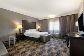 A hotel room with a bed, bedside tables, a desk, a chair, and a television. - Best Western Plus Midwest Inn (Omaha)