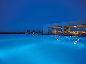 Un hotel moderno con piscina, asientos exteriores y vistas al océano.