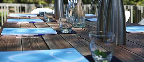 A wooden table with metal pitchers, glasses, and notepads.
