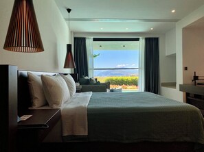 A modern hotel room with a large bed, a desk, and a view of the outdoors. - Thalatta Seaside Hotel (Mantoudi-Limni-Agia Anna)