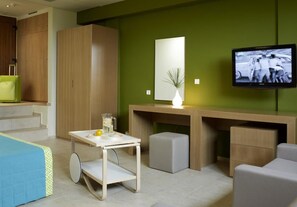 A modern room with a desk, a television, a bed, and a green wall.