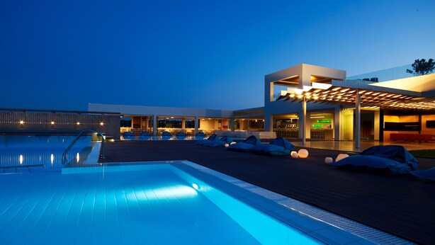 Un hôtel moderne doté d’une piscine, d’un espace extérieur aménagé et d’une zone couverte éclairée.