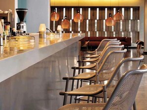 A modern bar area with a long counter, wicker chairs, and pendant lighting. - Thalatta Seaside Hotel (Mantoudi-Limni-Agia Anna)