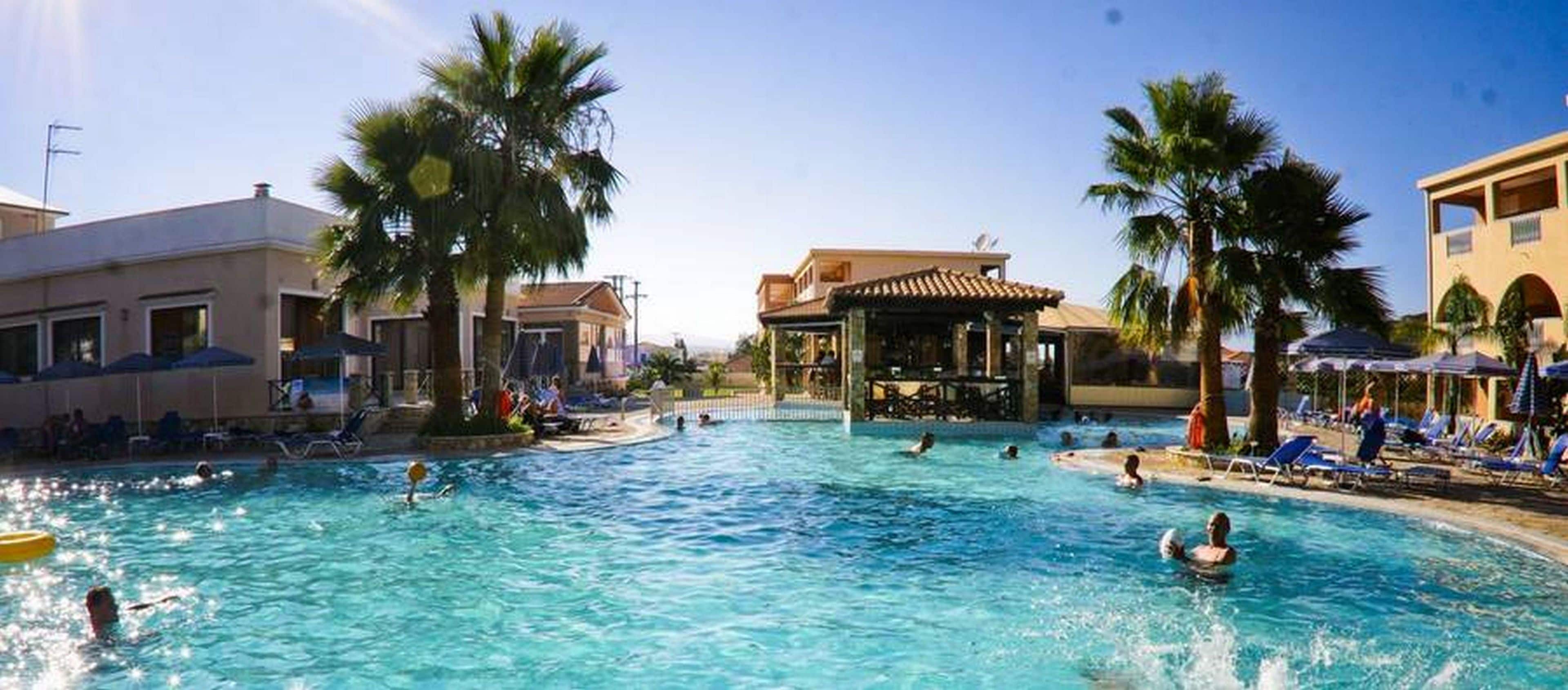 A swimming pool with lounge chairs and palm trees.