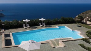 A swimming pool with a view of the ocean, surrounded by lounge chairs and umbrellas. - Niforos Panorama (Kefalonia)