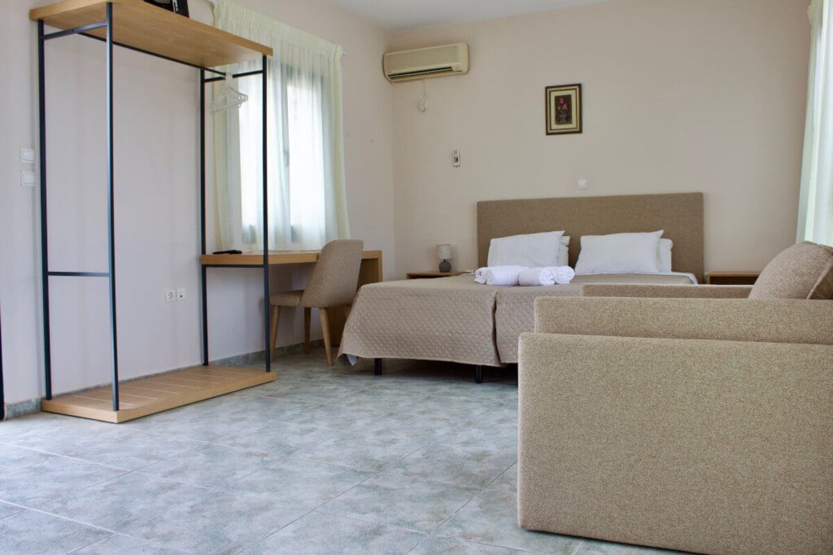 Ein Hotelzimmer mit Bett, Schreibtisch, Stuhl, Sofa und Kleiderschrank.