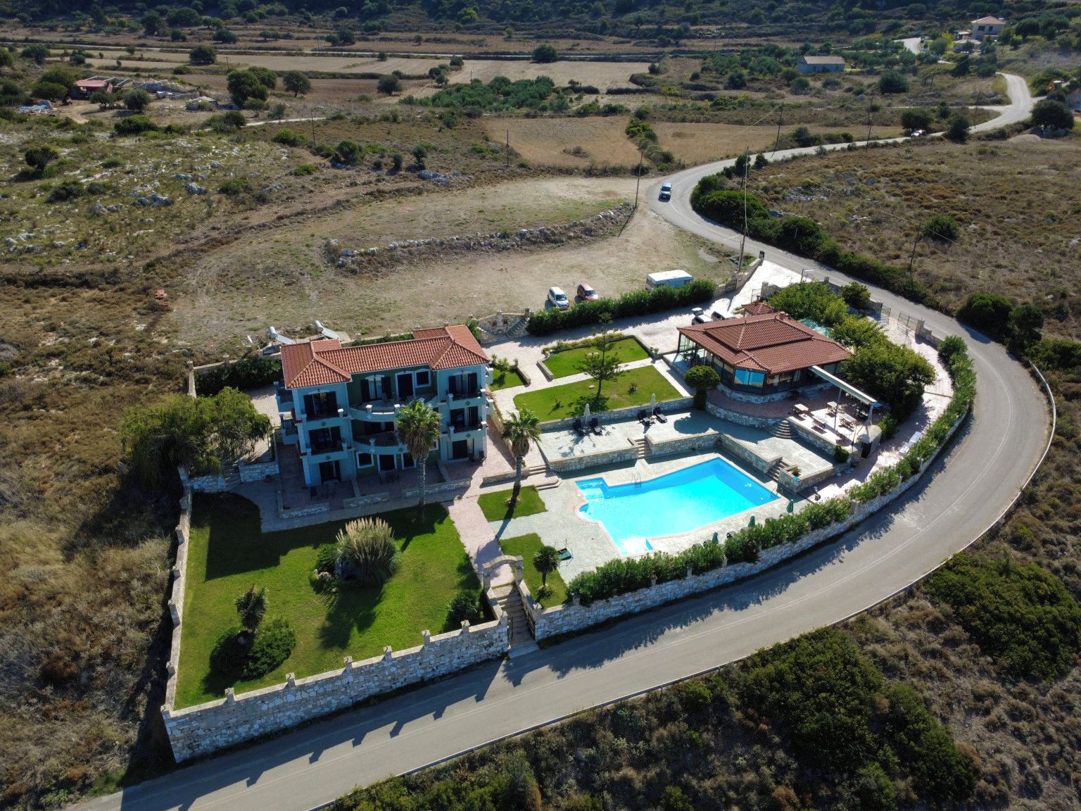 A large estate with a swimming pool, multiple buildings, and a winding road.