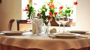 Mesa lista para comer con platos blancos, copas de vino y una jarra.