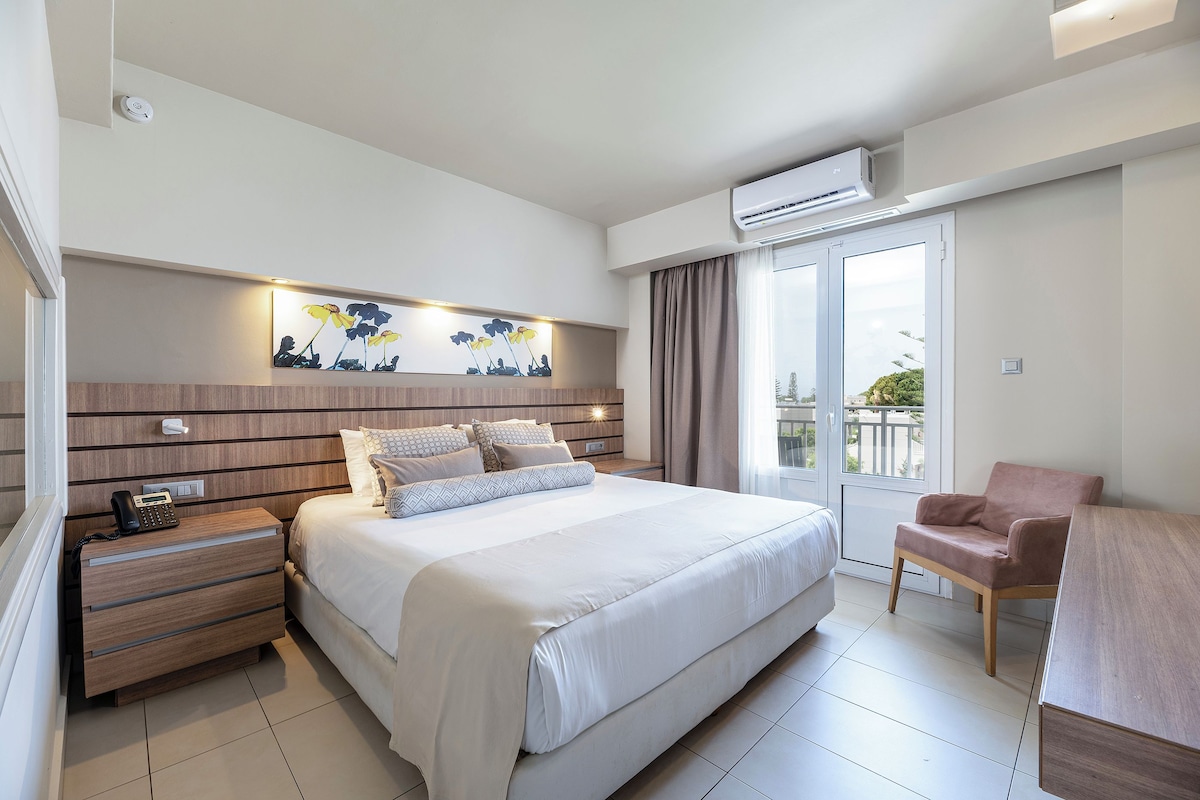 Una habitación de hotel moderna con una cama grande, mesitas de noche, un escritorio y una silla.