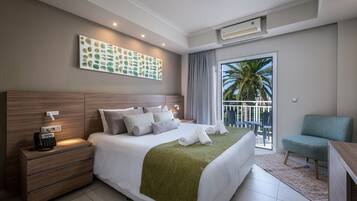 Habitación de hotel moderna con una cama grande, teléfono en la mesita de noche, un escritorio y vistas a palmeras a través de la ventana.