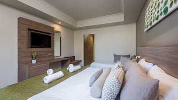 Habitación de hotel con una cama grande, televisión de pantalla plana, cómoda de madera y un cuadro en la pared.