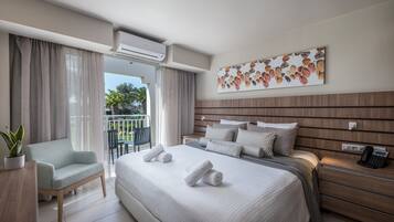Una habitación de hotel moderna con una cama grande, un área de descanso con una silla, un balcón con cortinas y un aire acondicionado instalado en la pared.
