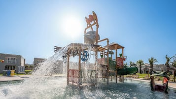 Una fuente de agua con una escultura de pájaro, rodeada por una piscina y edificios al fondo.