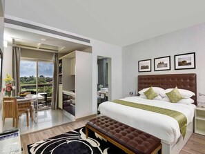 Quarto de hotel moderno com uma cama grande, uma escrivaninha e vista para o exterior.