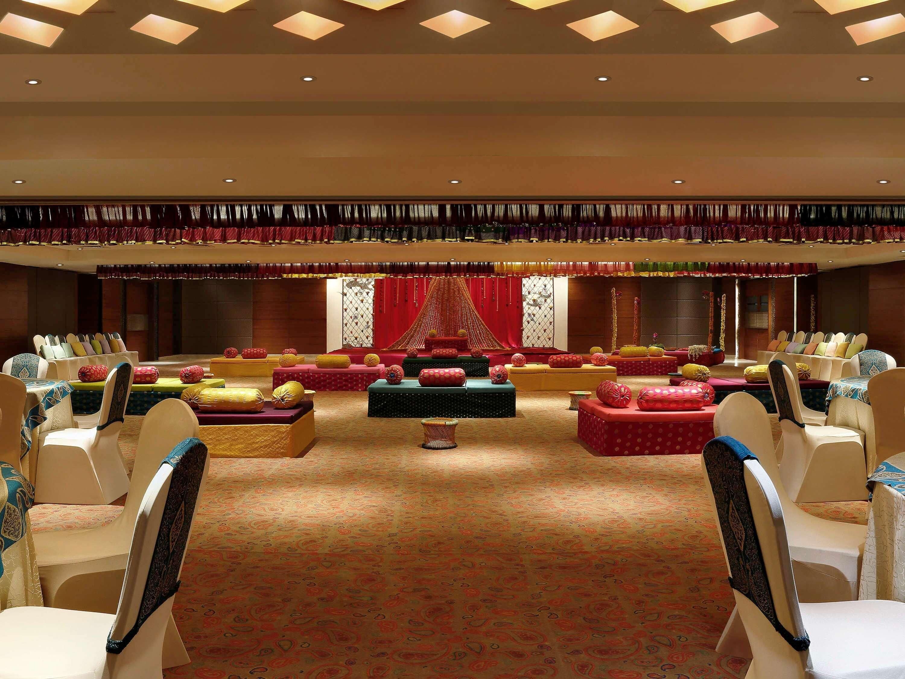 A spacious hall with tiered seating, a stage with red drapery, and a patterned carpet.
