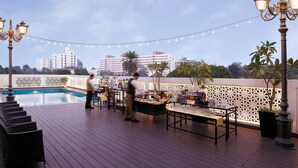 A rooftop pool area with a bar, lounge chairs, and string lights. - Grand Mercure Vadodara Surya Palace (Vadodara)