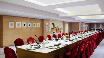 A conference room with a long table, red chairs, microphones, and a neutral color scheme.