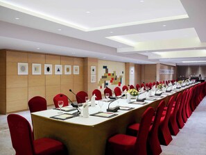 A conference room with a long table, red chairs, microphones, and a neutral color scheme.