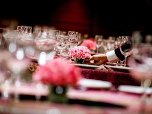 Een gedekte tafel met verschillende wijnglazen en een vaas roze bloemen.